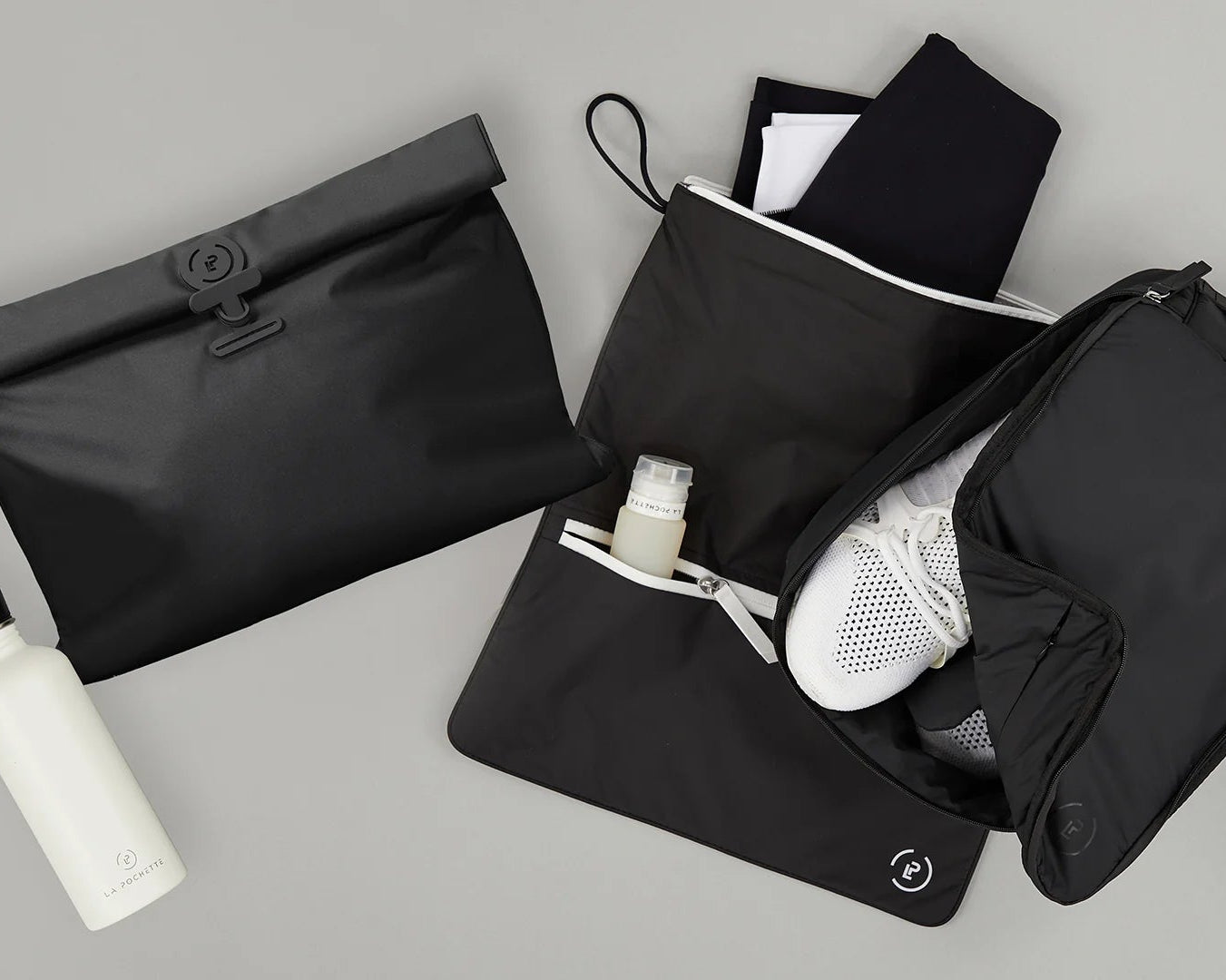 Black travel bags and a white bottle on a gray surface